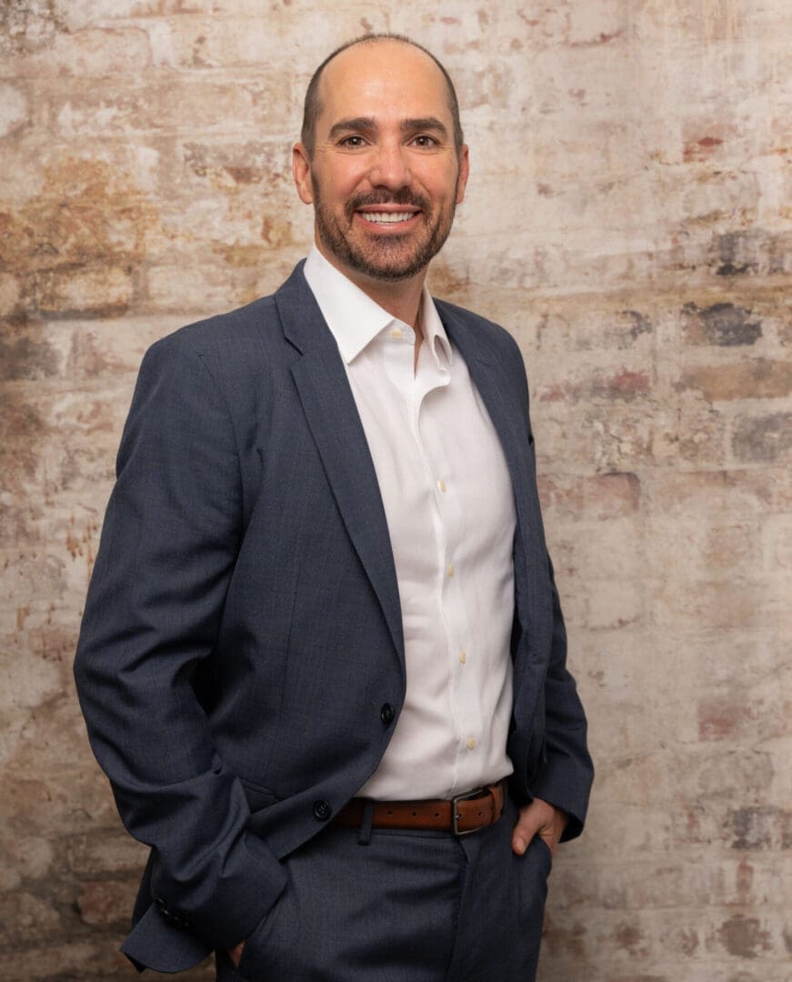 A man in a suit and tie standing next to a brick wall.