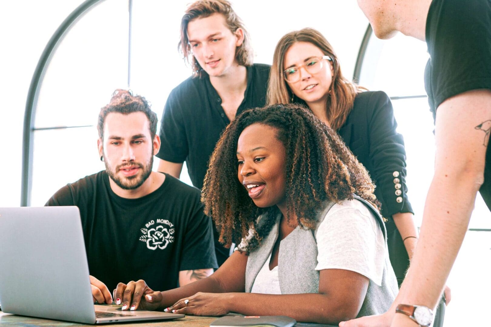 A group of people gathered around a laptop.